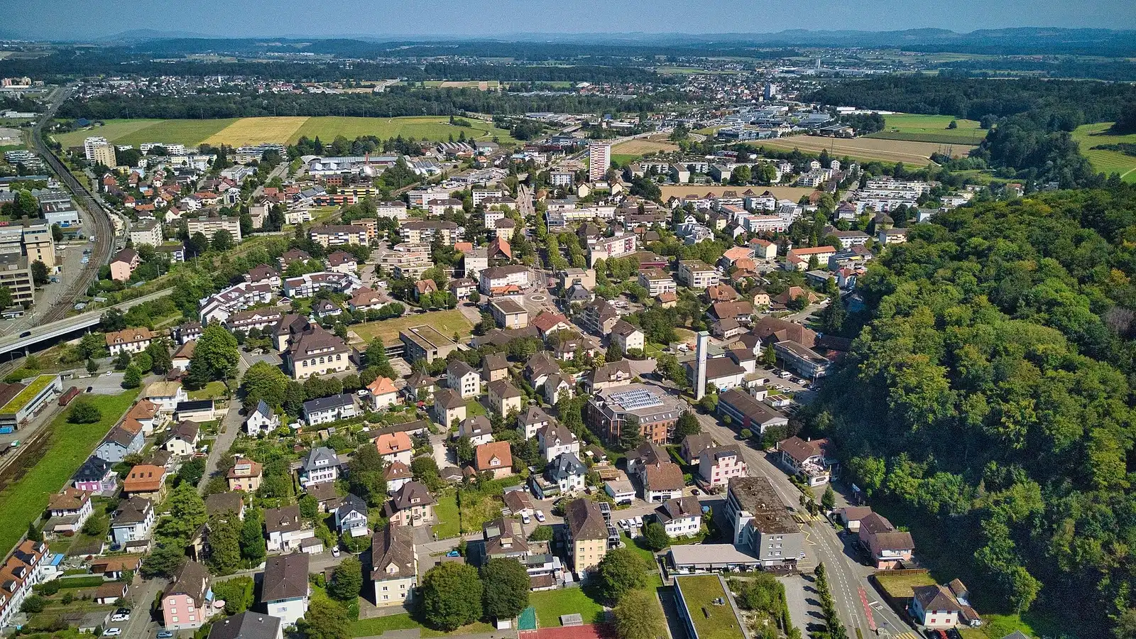 Blick über Zuchwil mit Wohnhäusern, Grünflächen und der Kirche im Vordergrund.